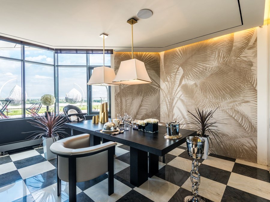 Dining room with a tonal palm-leaf mural along one wall, pendant lamps and a chequerboard floor