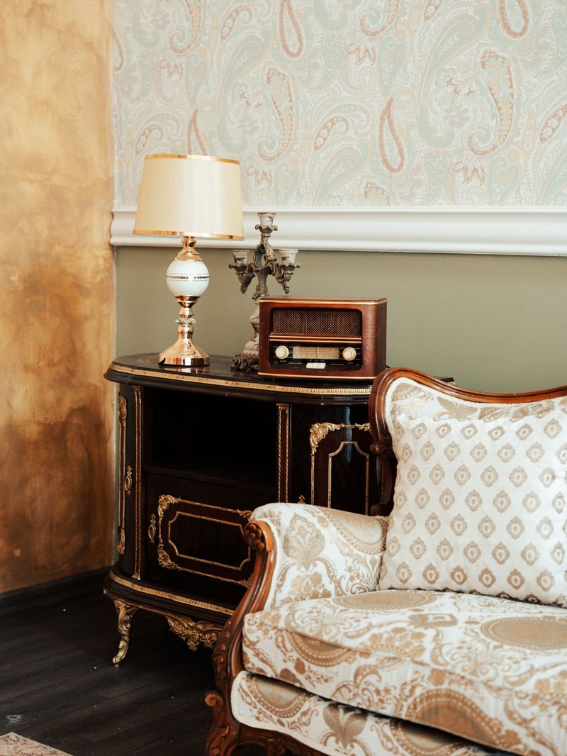 Traditional sitting room corner with pale paisley wallpaper above a painted dado rail