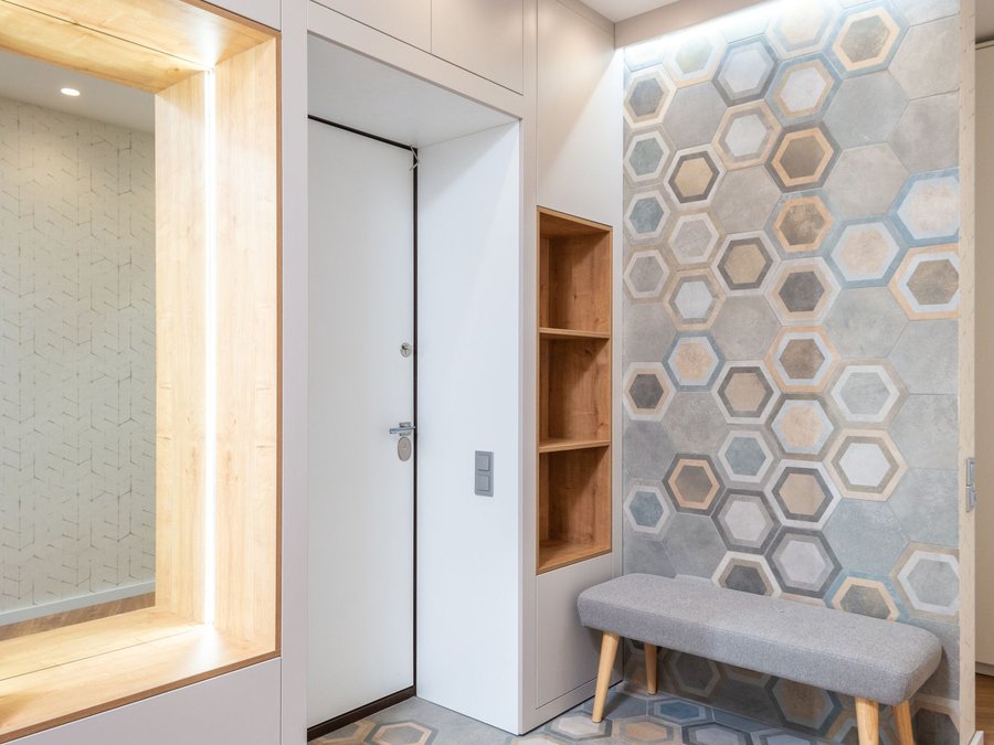 Entryway wall finished with a hexagonal patterned panel above a bench and shelving