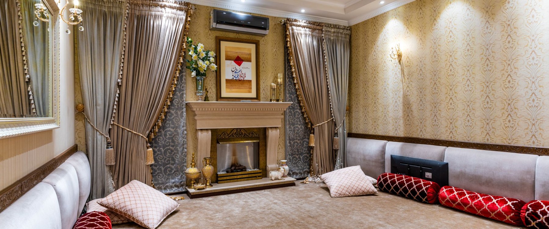 Formal living room with ornate damask wallpaper running the length of the wall beside a marble fireplace
