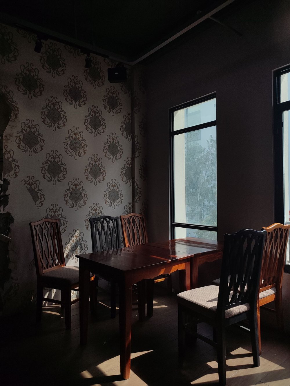 Dining room corner papered in a muted grey damask, lit from a tall window